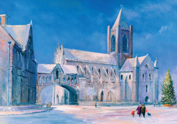 Snow-covered Christ Church Cathedral in Dublin, with a Christmas tree and people walking, under a bright blue sky