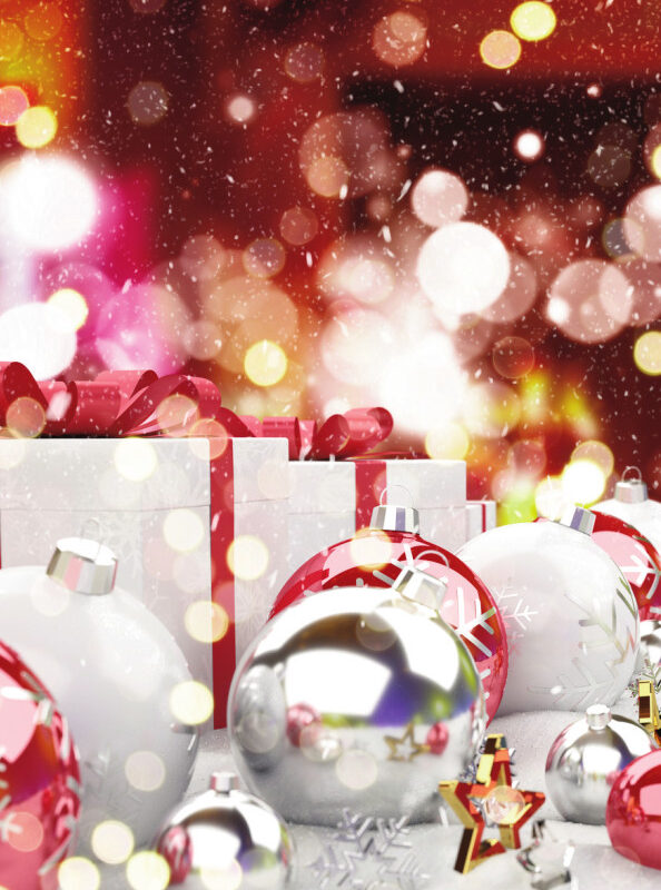 Colorful Christmas ornaments and wrapped gifts are scattered on a snowy surface, with a festive bokeh background