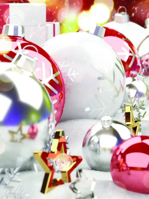 Colorful Christmas ornaments, including red and white balls with snowflake designs, scattered on a snowy surface with gifts