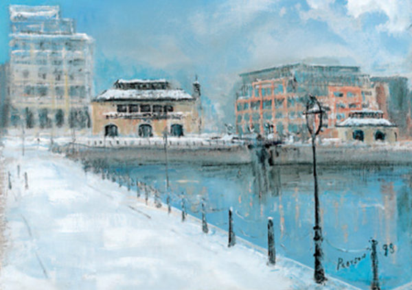 Snow-covered waterfront scene featuring buildings, a lamppost, and a calm river under a blue sky