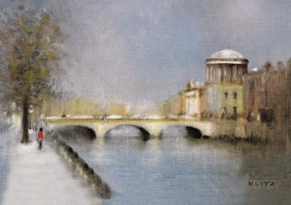 Snowy riverside scene featuring The Four Courts, a bridge, and a lone figure walking along the path. The Four Courts Christma